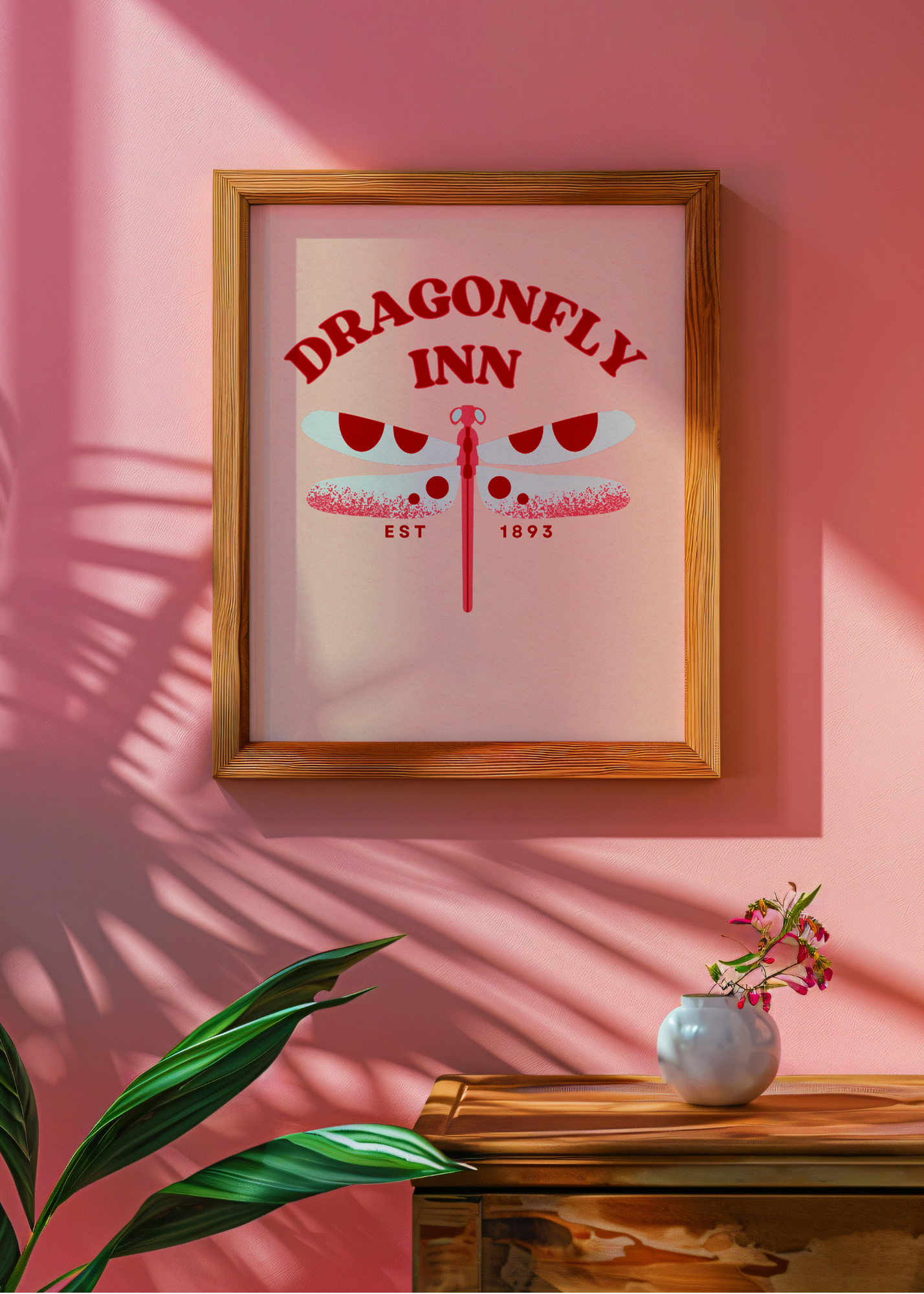 Framed poster with 'Dragonfly Inn' design on a pink wall.