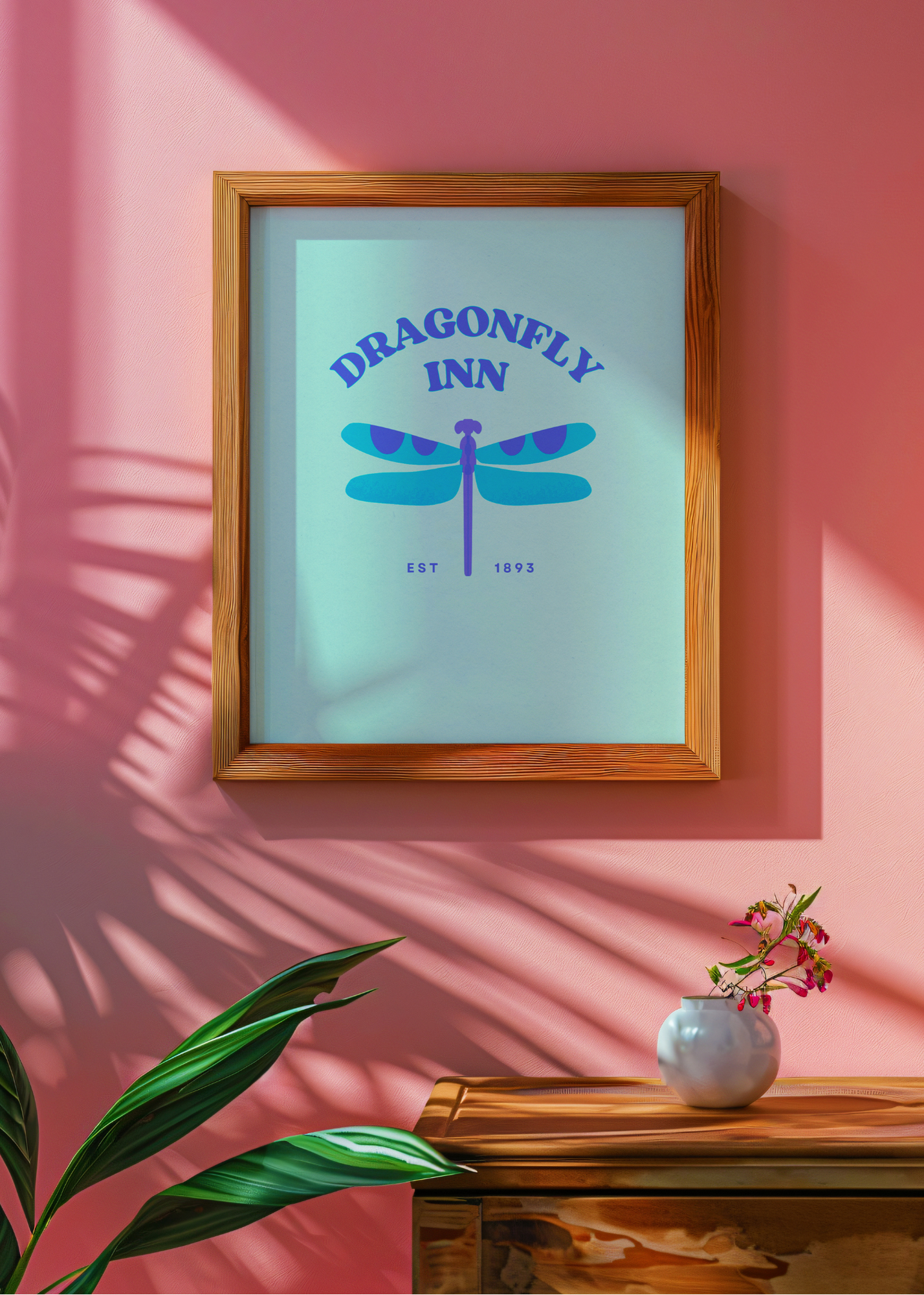 Framed artwork with 'Dragonfly Inn' design on a pink wall.