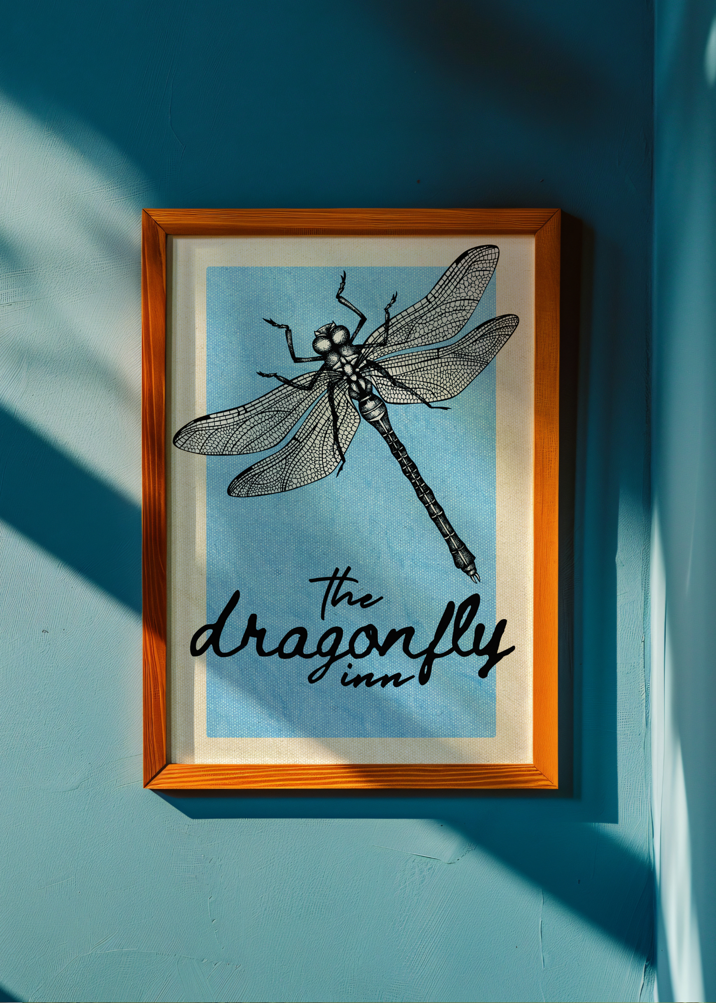 Framed artwork of a dragonfly with 'The Dragonfly Inn' text on a blue background