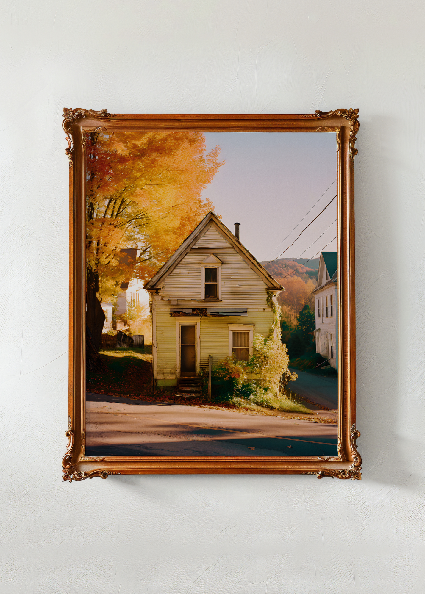 Framed photograph of a house with autumn trees on a white wall