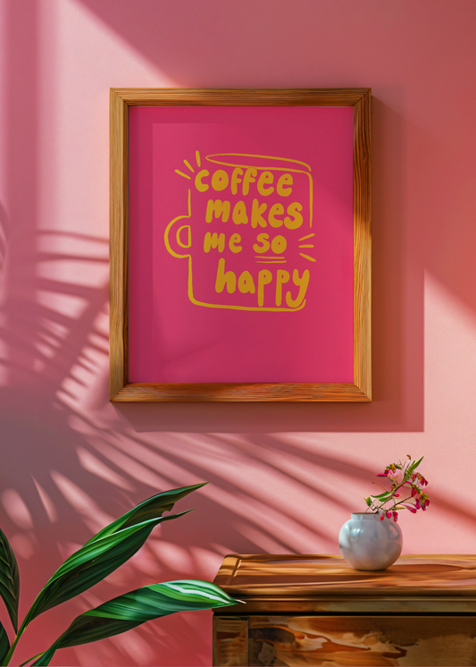 Framed pink poster with yellow text 'coffee makes me so happy' on a pink wall with a plant and vase in the foreground.