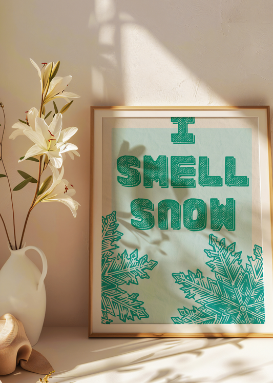 Framed artwork with 'I Smell Snow' text and snowflake designs on a light background.