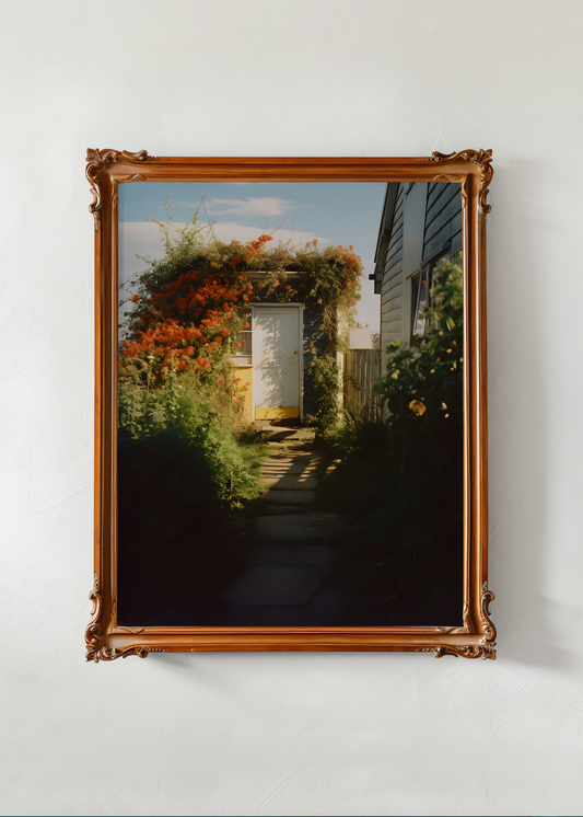 Framed photograph of a garden scene with a wooden frame on a white wall.