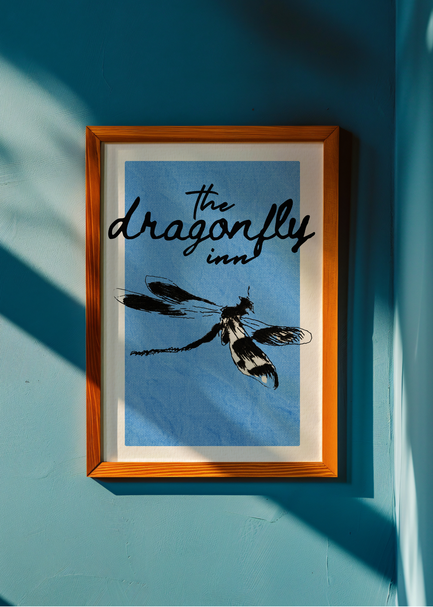 Framed artwork with 'The Dragonfly Inn' text and dragonfly illustration on a blue background.